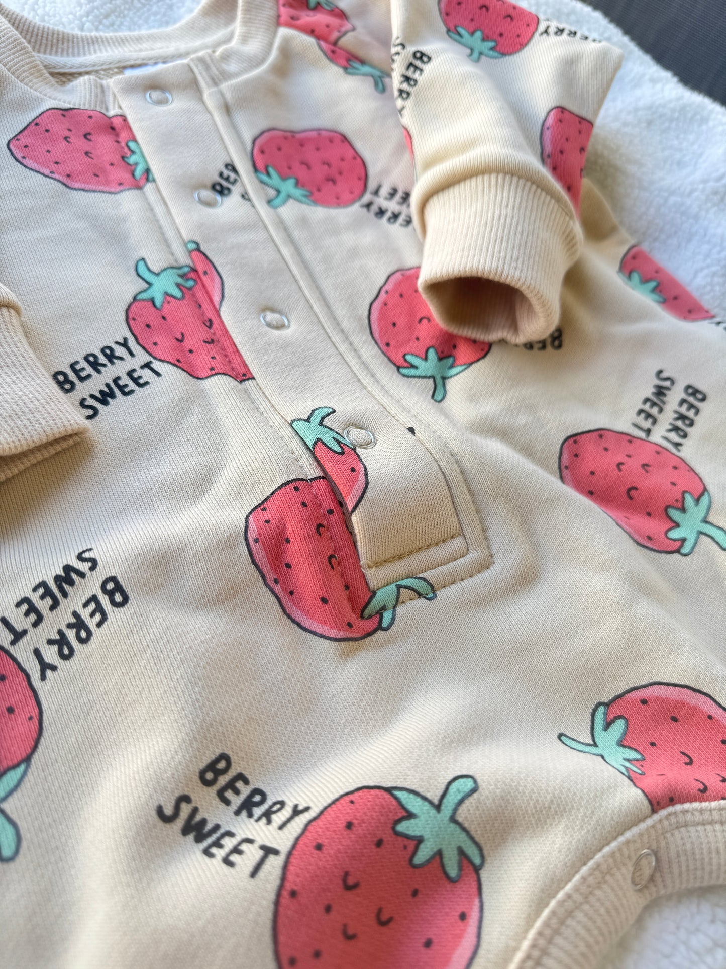 Close-up of Berry Sweet kids coverall showing strawberry print, cotton fabric and front snap buttons.